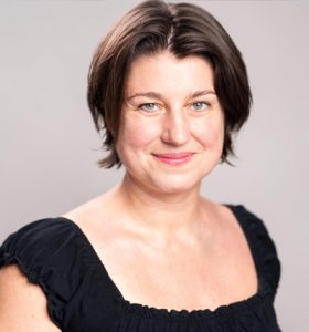 Head and shoulders photo of Executive Director Anna Kajtar. She is wearing a black short-sleeved top and looking directly at the camera.