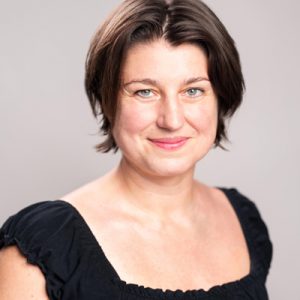 Head and shoulders photo of Executive Director Anna Kajtar. She is wearing a black short-sleeved top and looking directly at the camera.